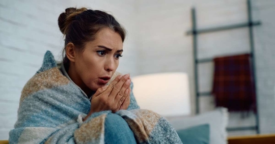 woman wrapped in blanket trying to warm herself